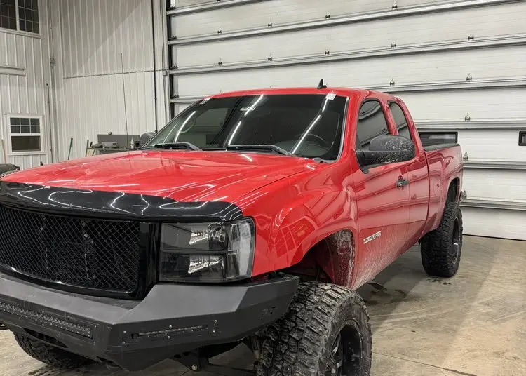 Lifted pickup truck getting a mobile windshield replacement in a shop bay