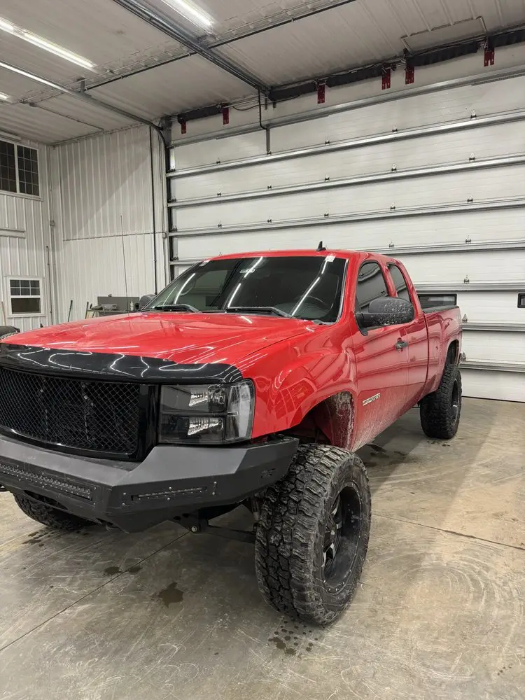 Lifted pickup truck getting a mobile windshield replacement in a shop bay